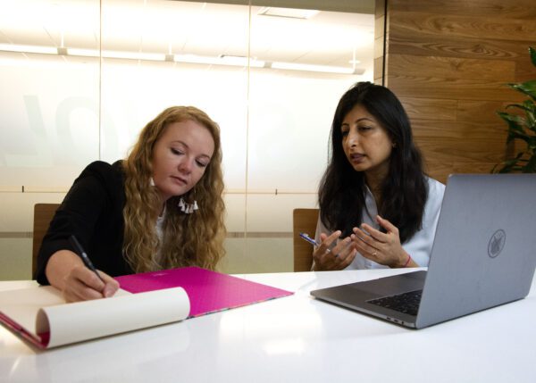 Taylor Waters (pictured left) takes notes while speaking with a Fidelity employee.