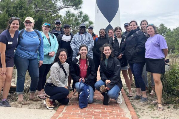A group of Mountains to Sea Scholars pose in front the Cape Lookout lighthouse during an excursion to the Outer Banks. Empowering educators is a core function of the Kenan Fellows Program.