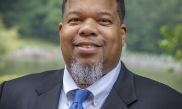 Headshot of Purdie wearing a gray blazer and a blue tie.