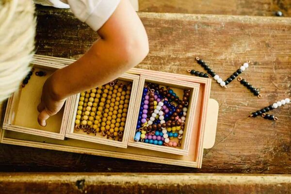 Hands of a child manipulating educational materials to learn to count in a Montessori classroom.