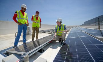 Clean energy workers inspecting a solar panel