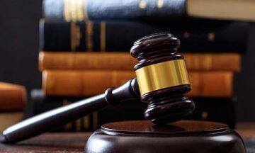 Law gavel on a wooden desk, law books background