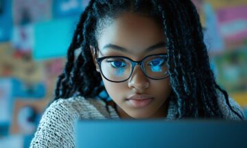 Student wearing glasses working on a laptop