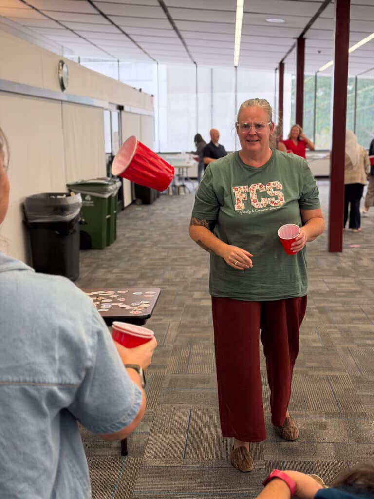 Fellows try to catch a cup in a cup as part of a feedback giving exercise.