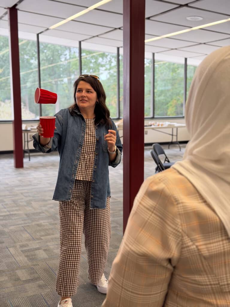 Fellows try to catch a cup in a cup as part of a feedback giving exercise. 